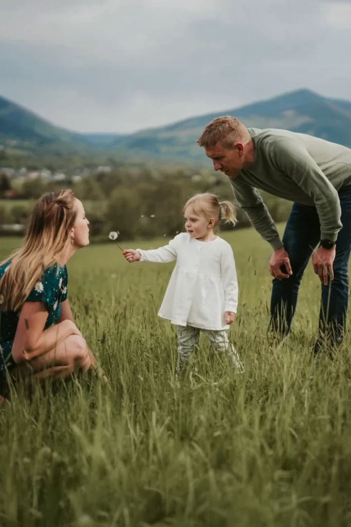 Recenze – rodinné focení: rodiče s malým dítětem na louce, přirozený moment při hře v přírodě s horami v pozadí.