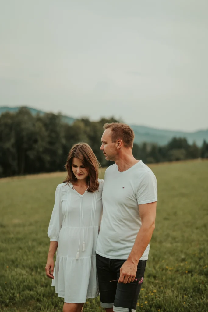 Recenze „Těhotenské focení – Leona G.“ – přirozený portrét páru na louce v jemném večerním světle.