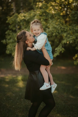 Maminka drží malou dceru v náručí při focení v přírodě