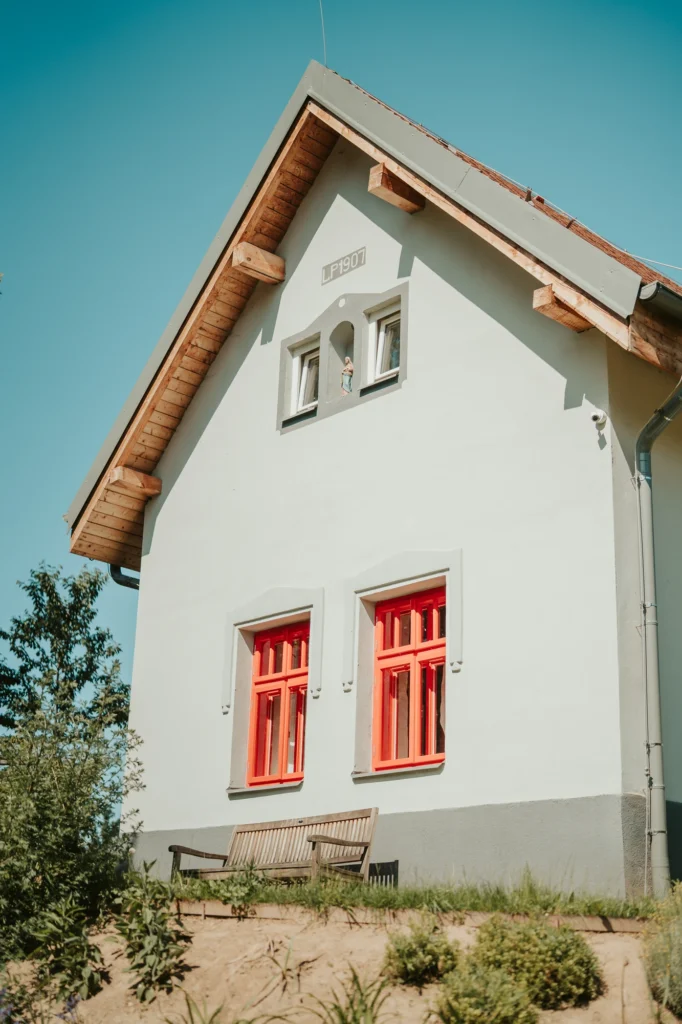 Štít bílého domu s červenými okny na Samotě Hojšín