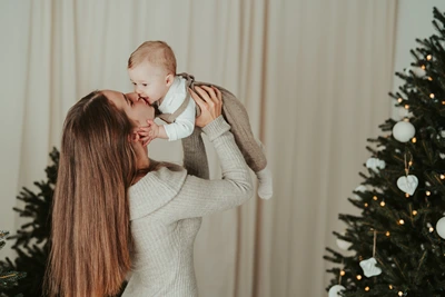Maminka dává miminku pusu u vánočního stromku